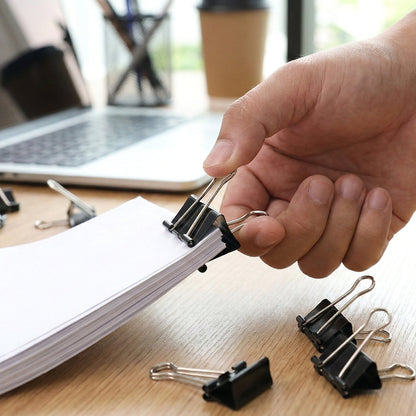 Black metal binder clips securing paper stacks