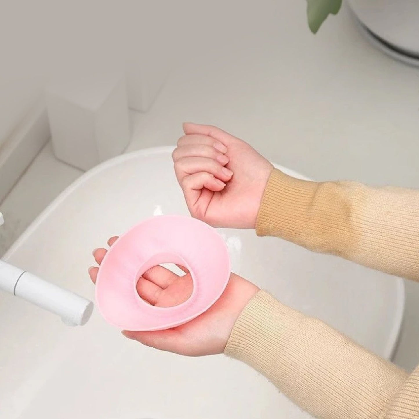 Person wearing pink silicone wrist band while washing face to prevent water drips