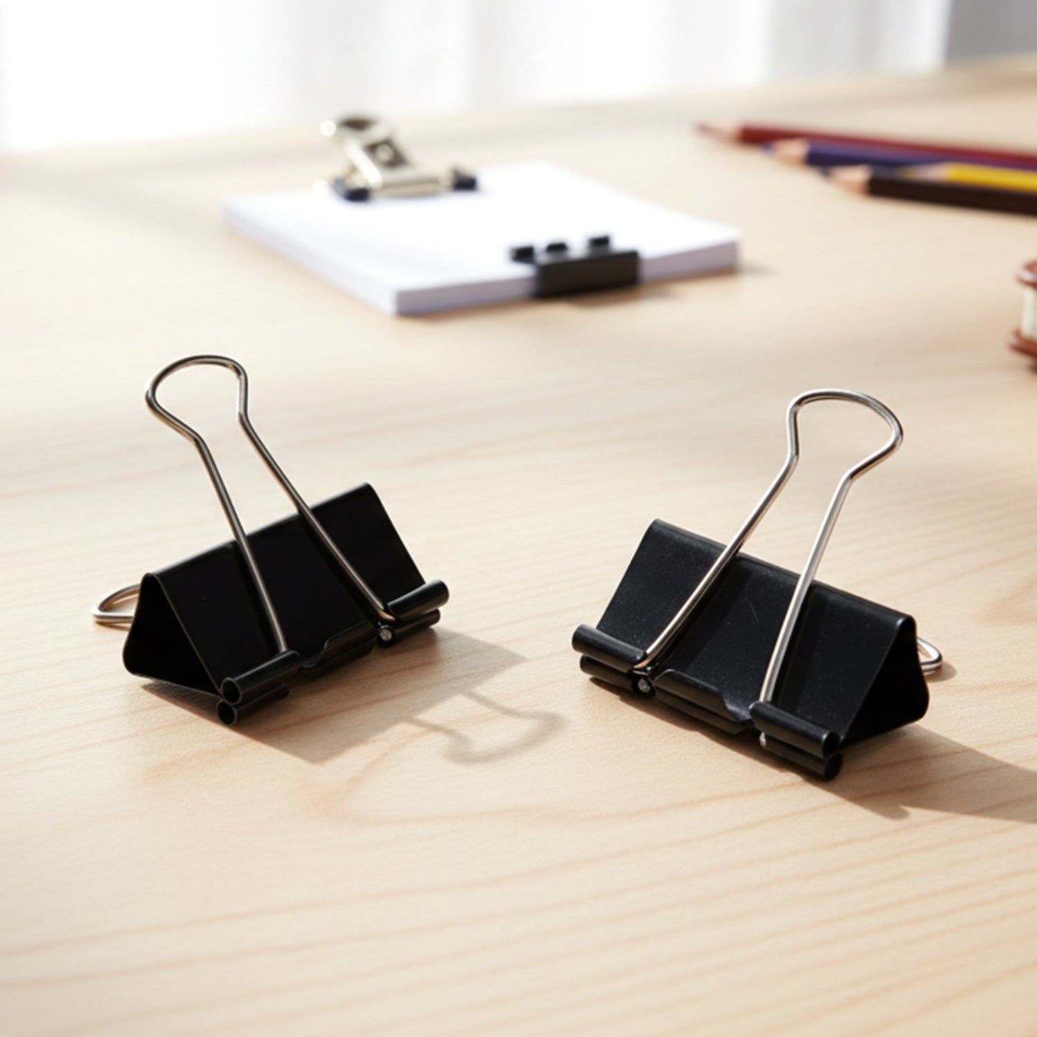 Single black metal binder clip holding papers