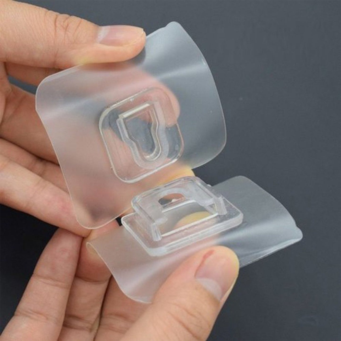 Transparent adhesive hook holding an item on a wall, showcasing its utility.