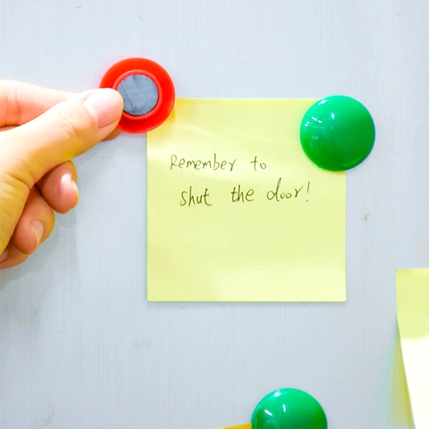 Magnetic buttons adhering to a metal cabinet, demonstrating strong hold.