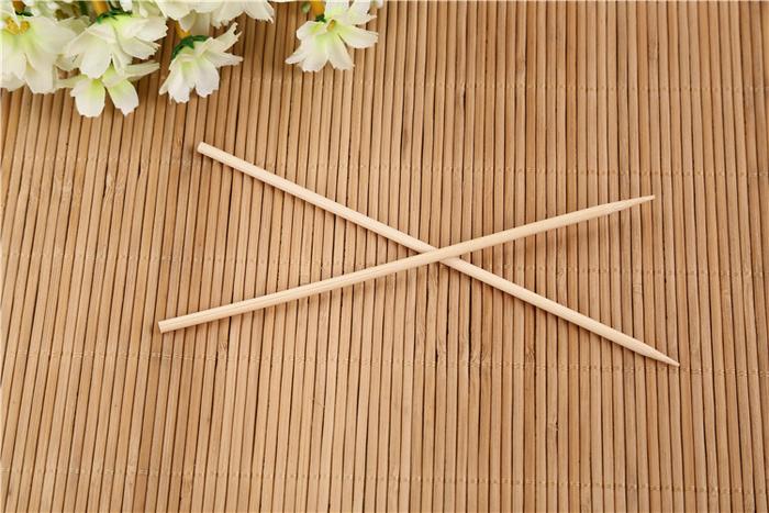 A hand holding a bamboo BBQ skewer with various ingredients for grilling.